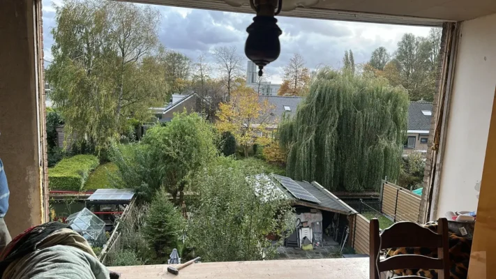 Uitzicht vanuit de woning tijdens de werkzaamheden in Zoetermeer – voorbereide opening voor de plaatsing van nieuwe kozijnen en grote glaspartijen met uitzicht op de tuin vóór de montage door Avalanche Windows.