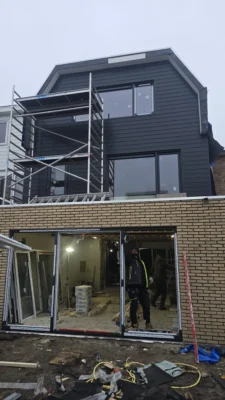 Achtergevel van de woning tijdens de complete renovatie in Amstelveen met montage van grote schuifdeuren en een nieuwe dakopbouw