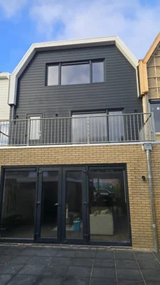 Achtergevel van de woning na de complete renovatie in Amstelveen met nieuwe dakopbouw, balkon en grote glaspartijen