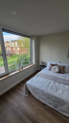 Lichte slaapkamer na de complete renovatie van een woning in Amstelveen met groot raam en moderne interieurafwerking