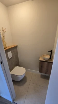 Modern toilet na de complete renovatie van een woning in Amstelveen met minimalistische afwerking en houten accenten