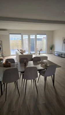Moderne woonkamer en eetkamer na de complete renovatie van een woning in Amstelveen met grote glaspartijen en toegang tot de tuin