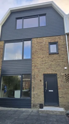 Vooraanzicht van de woning na de complete renovatie in Amstelveen met nieuwe dakopbouw, voordeur en Keralit gevelbekleding